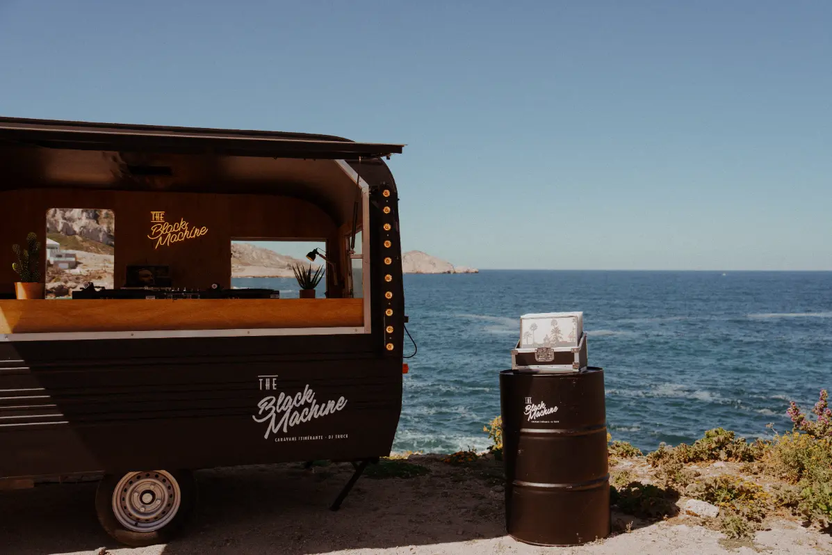 Détail de la caravane DJ The Black Machine avec mallette à vinyles face à la mer