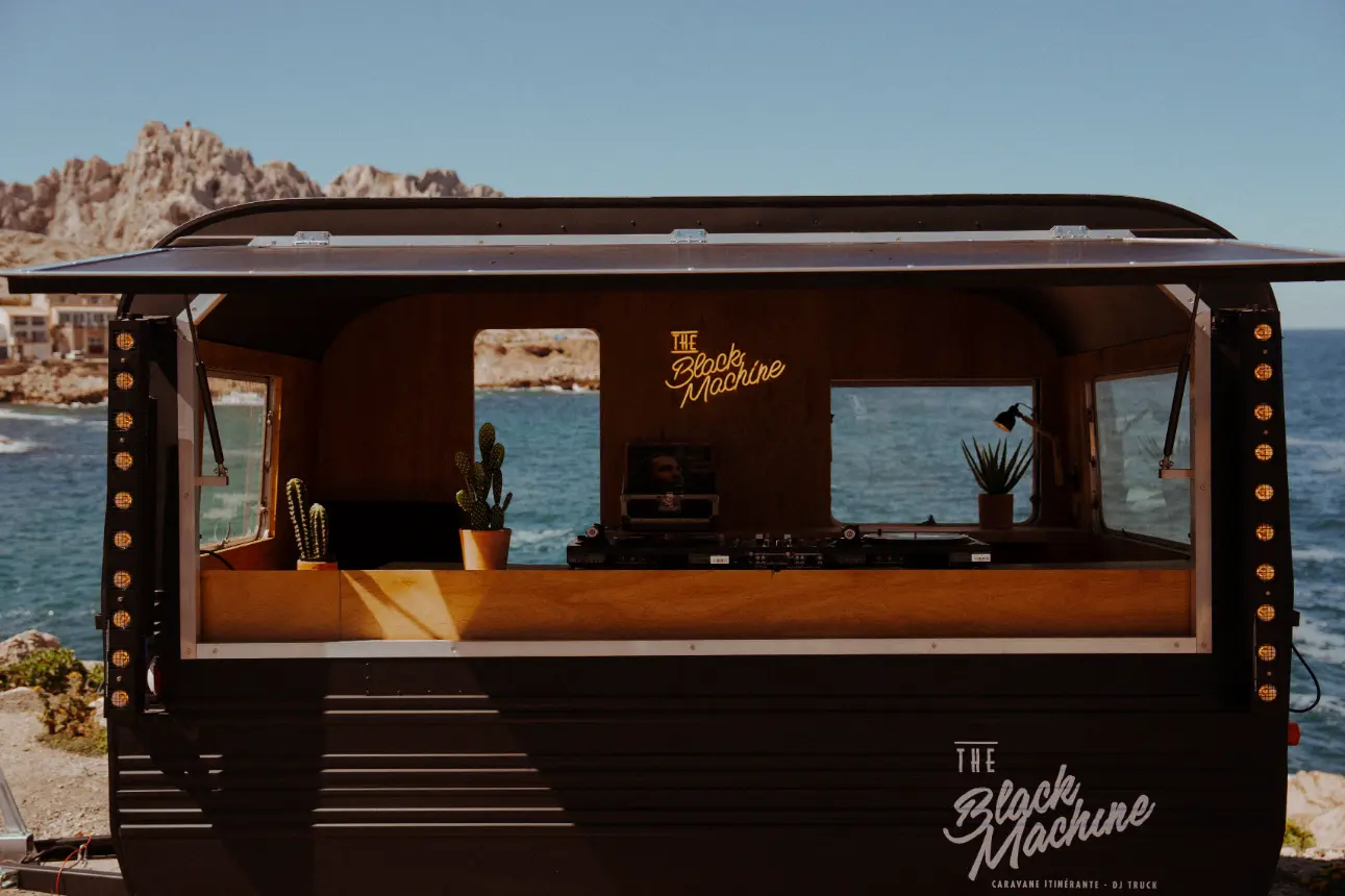 Intérieur de la caravane DJ The Black Machine avec platines vinyles et décoration soignée en bord de mer